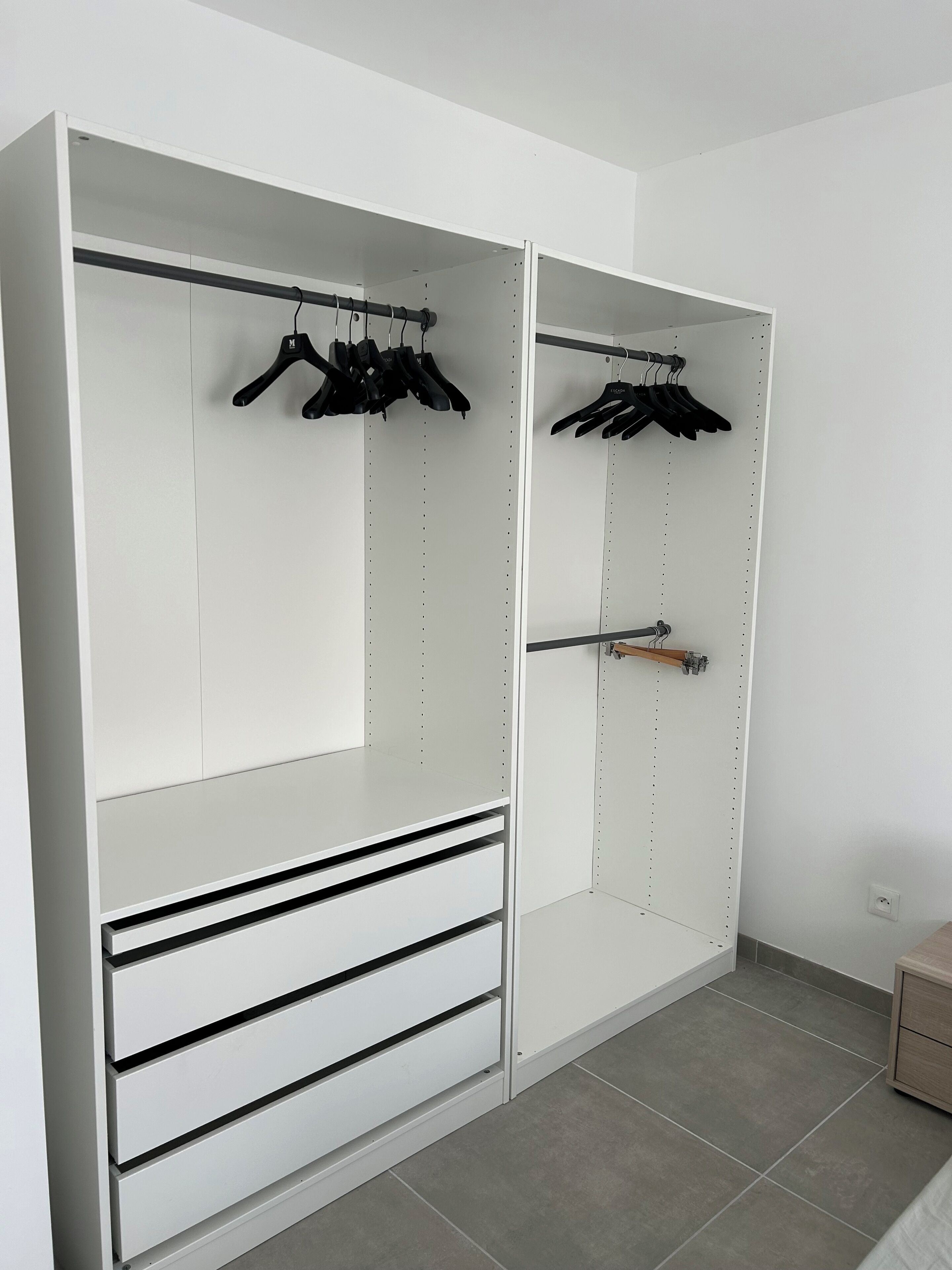 A walk-in closet with multiple shelves and hanging space, featuring a minimalist design and neutral color palette.