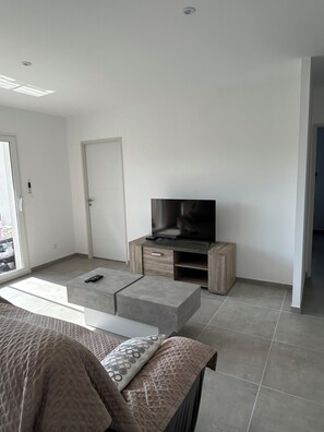 Relax in this stylish living room with a flat-screen TV, comfortable sofa, and sliding door to an outdoor area.