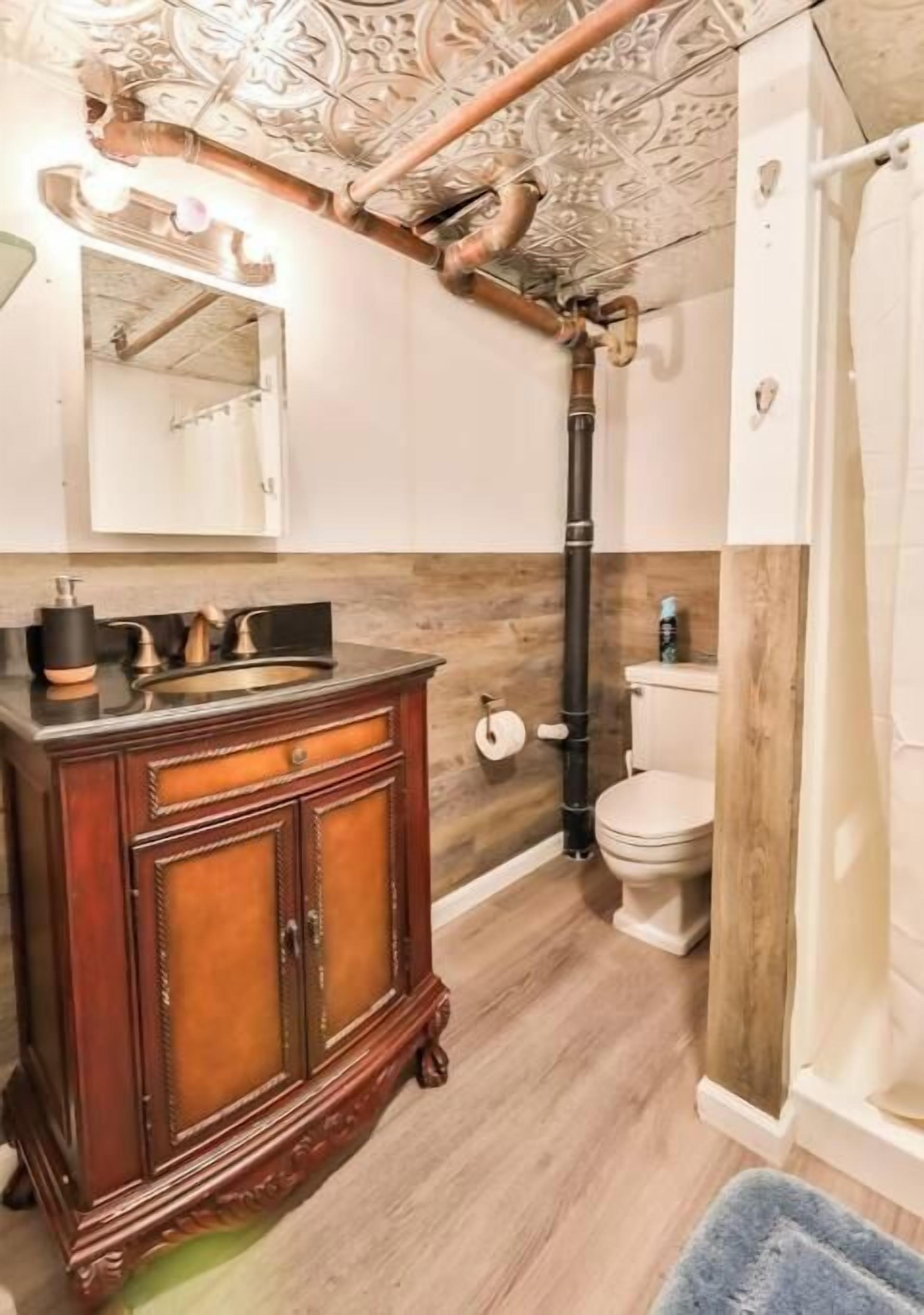 A bathroom with a wooden vanity, a toilet, and a shower area.