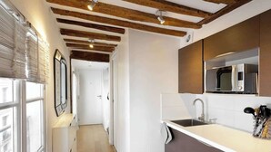 Una cucina moderna con travi in legno, un piano di lavoro bianco e un forno a microonde integrato.