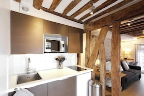 A modern kitchen with a built-in microwave, stainless steel sink, and wooden beams.