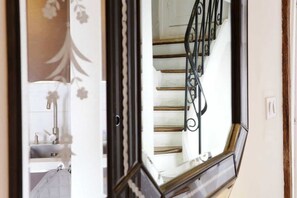 Una escalera con barandilla de metal negro y pared blanca con estampado floral.