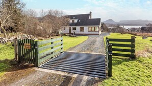 Une maison avec une allée en gravier menant à un portail en bois.