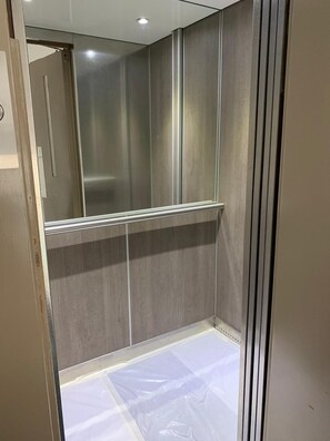 Un baño moderno con espejo, zona de ducha y suelo de baldosas.