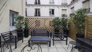An outdoor patio with a wooden lattice wall, black metal furniture, and potted plants.