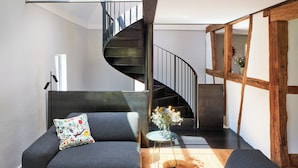 Un intérieur moderne avec un escalier en colimaçon, un canapé, une petite table ornée de fleurs et un plancher en bois.