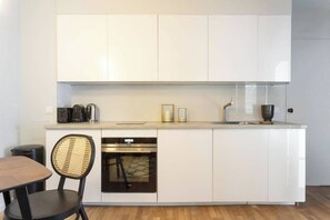 A modern kitchen with white cabinetry, a built-in oven, and a coffee maker.