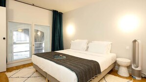 Ein modernes Schlafzimmer mit einem großen Bett, einem Nachttisch, einem Heizgerät und Blick durch eine Glastür.