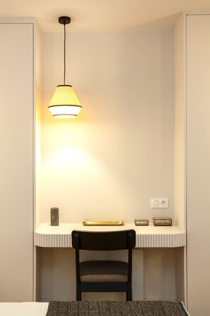 Une petite pièce moderne équipée d’un bureau, d’une chaise, d’une lampe et d’une prise de courant.