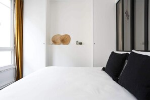 Quarto com uma cama grande, um guarda-roupa e uma janela com cortinas.
