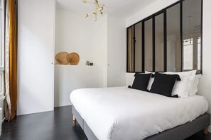 A modern bedroom with a large bed, a mirror, and a unique ceiling light fixture.