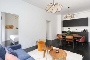 Uma sala de estar moderna com um sofá, mesa de centro e área de jantar com cadeiras e mesa.