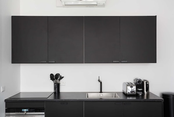 A modern kitchen with dark cabinets, a stainless steel sink, and a coffee maker.