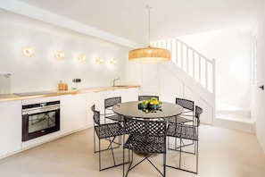 A modern kitchen with a round dining table, black chairs, and a hanging light fixture. - Grand apartment with character facing the Louvre - 3 bedrooms - A/C - up to 8 guests - Rivoli III by Habitat Parisien (Paris)