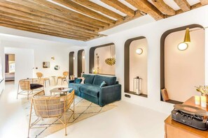A modern living room with a blue sofa, wooden chairs, a coffee table, and a record player.