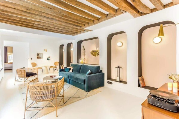A modern living room with a blue sofa, wooden chairs, a coffee table, and a record player.