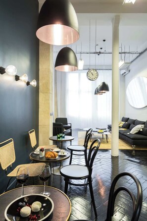 Uma sala de estar moderna com área de jantar, apresentando uma mesa grande com cadeiras, um sofá e iluminação pendente.
