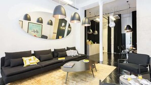 A modern living room with a black sofa, a coffee table, and pendant lights.