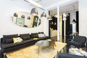 A modern living room with a black sofa, a coffee table, and pendant lights.