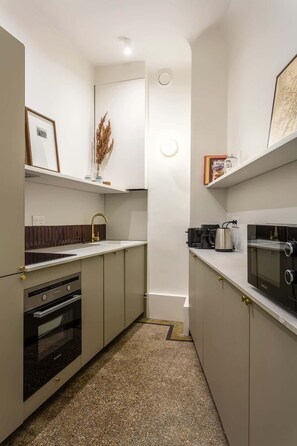 A compact kitchen with a built-in oven, a microwave, and a coffee maker on the countertop.