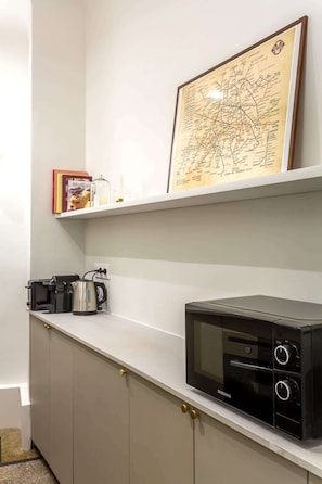 A kitchen with a microwave, coffee maker, and a framed map on the wall.