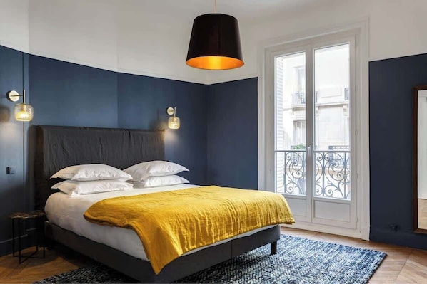 A bedroom with a bed, a black lamp, a window, and a door.