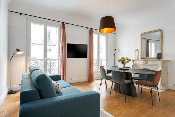 Un salon moderne comprenant un canapé, une table à manger, des chaises et une cheminée.