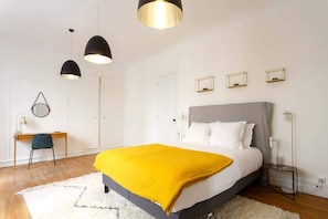 Quarto moderno com cama grande, escrivaninha e duas luminárias pendentes.