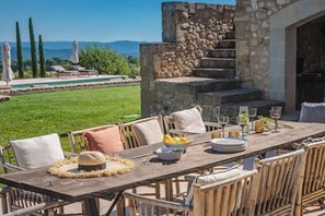 An outdoor dining area with a stone staircase, a pool, and a view of the mountains.