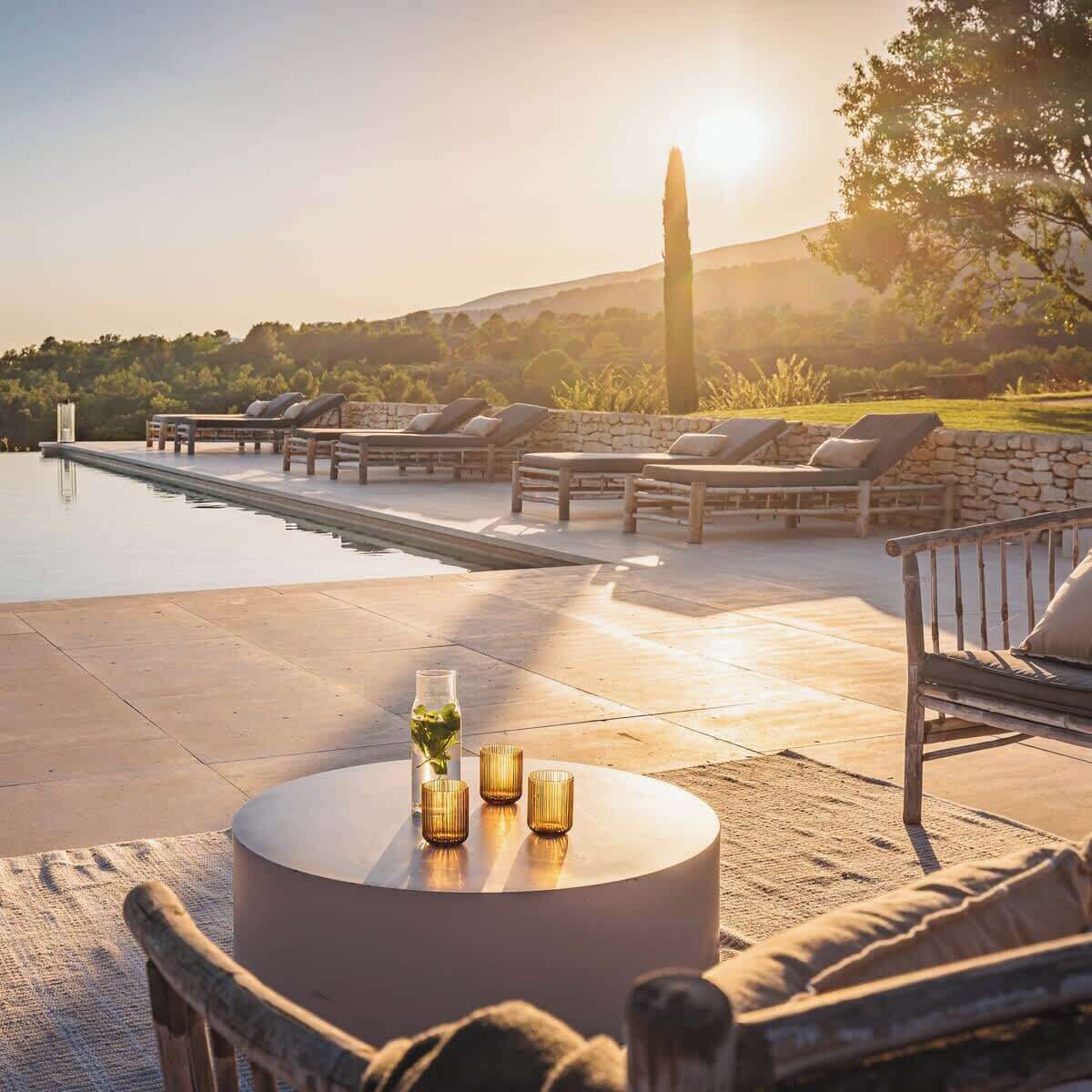 A poolside area with lounge chairs and a round table with candles.