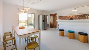 A modern kitchen with a wooden table, bar stools, a refrigerator, and a decorative backsplash.