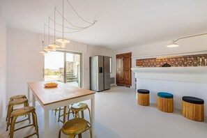 A modern kitchen with a wooden table, bar stools, a refrigerator, and a decorative backsplash.