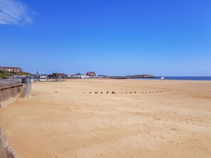 A beach with a clear sky, a sandy shore, and buildings in the background. - Sea Breeze is a delightful large family house a short stroll to the beach. (Gorleston)
