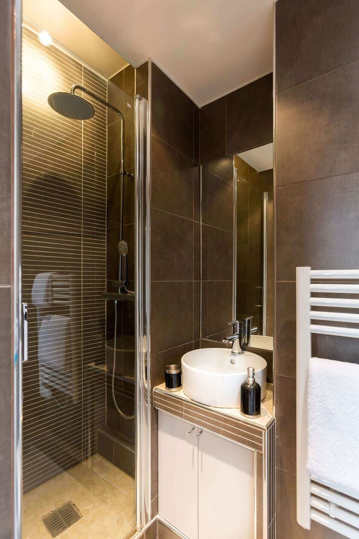 Une salle de bain moderne avec une douche à parois de verre, un lavabo blanc et un porte-serviettes.