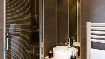Une salle de bain moderne avec une douche à parois de verre, un lavabo blanc et un porte-serviettes.