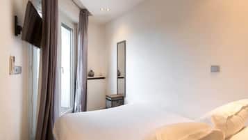 Une chambre d’hôtel avec un lit, une table de chevet, un miroir et une fenêtre avec des rideaux.