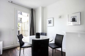 Un área de comedor moderna con una mesa redonda, sillas negras y un armario blanco.