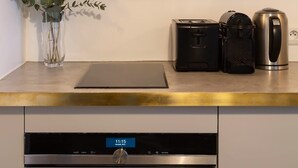 Uma cozinha com máquina de lavar louça, chaleira e torradeira na bancada.