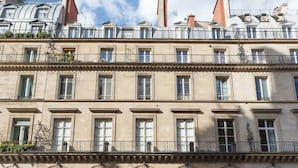 Um edifício de vários andares com estilo arquitetônico clássico, apresentando janelas em arco e varandas com grades.