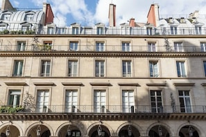 Un edificio de varios pisos con un estilo arquitectónico clásico, que presenta ventanas en arco y balcones con barandillas.