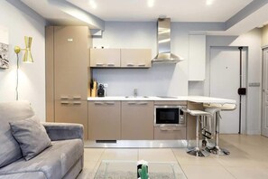 Una cocina moderna con armarios color beige, una campana extractora de acero inoxidable y una barra con taburetes.