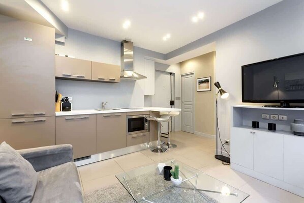 A modern kitchen with a built-in oven, a stainless steel range hood, and a bar stool.