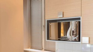 Eine kleine Küche mit Holzarbeitsplatte, integriertem Spülbecken und einem Fenster mit Jalousien.
