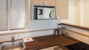 Eine moderne Küche mit Holzschränken, einer Edelstahlspüle und einem schwarzen Induktionskochfeld.