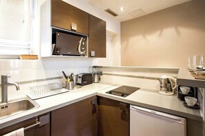 A modern kitchen with a dishwasher, a built-in oven, a microwave, and a coffee maker.
