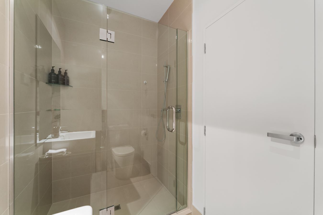 Un bagno moderno con doccia vetro, toilette e lavandino con articoli da toilette.
