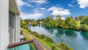 Un balcón con vista a un río, vegetación y cielo despejado.