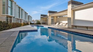 Piscina con sillas de descanso y vistas a edificios modernos.