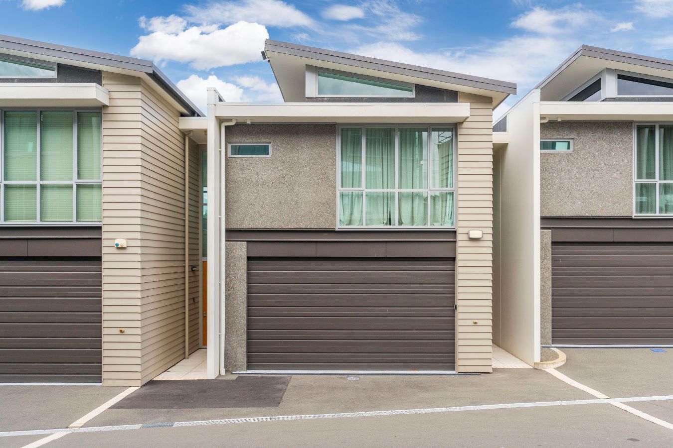 A row of modern, two-story houses with large windows and garage doors.