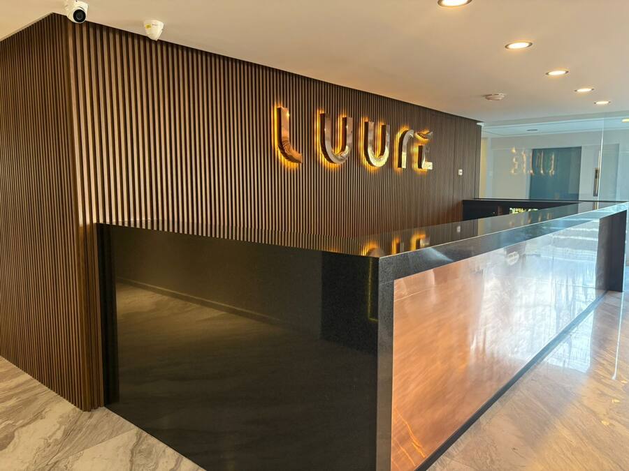 A reception desk with a modern design, featuring vertical wooden slats and illuminated letters spelling "LUXE".